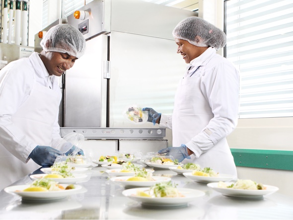 Two cooks preparing several plates of food 